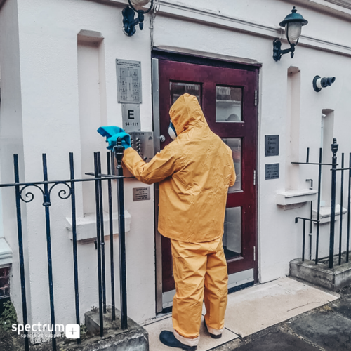 Man in PPE disinfecting touch plates