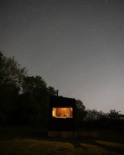 A cabin at night with the stars above.