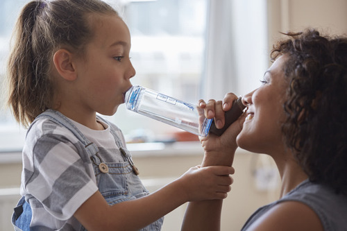 Mother helping daughter with inhaler